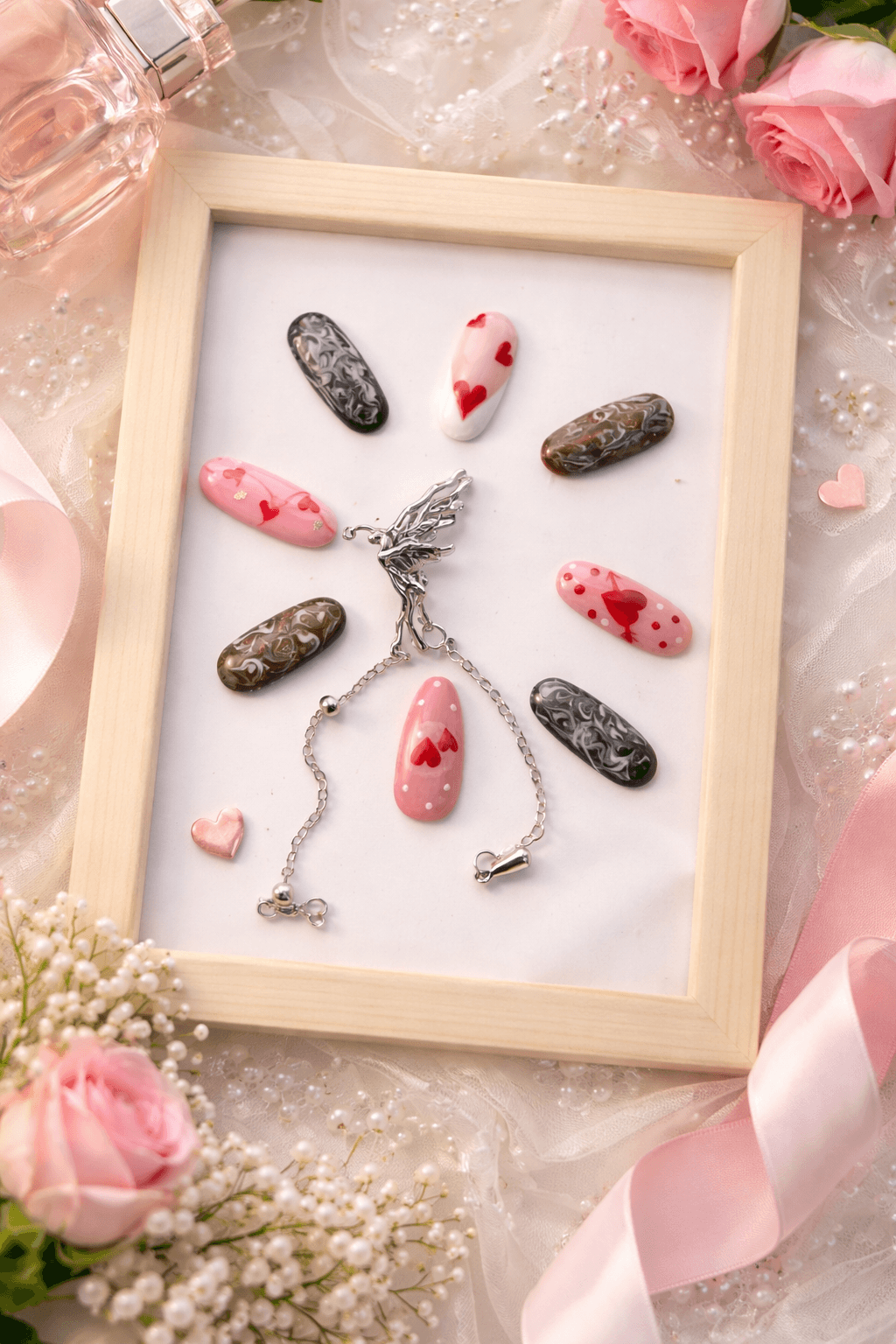 Ongles décorés de cœurs et marbrures dans un cadre en bois entouré de roses.