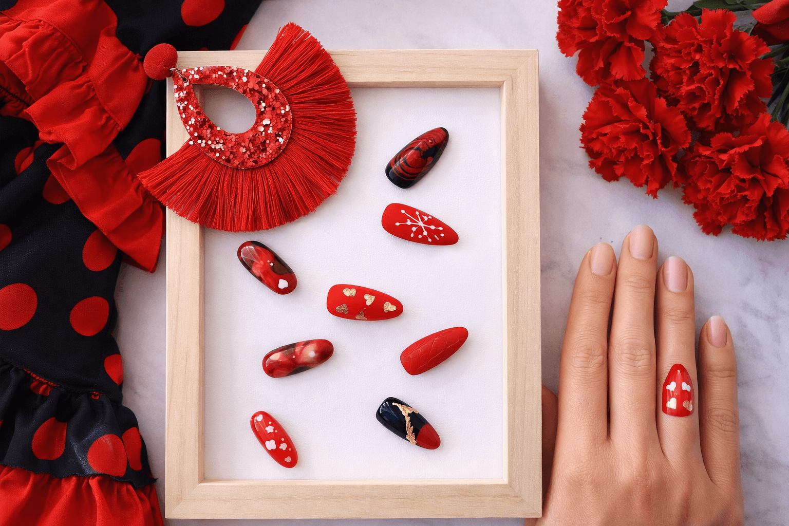 Faux ongles rouges et noirs décorés dans un cadre bois avec fleurs et main.